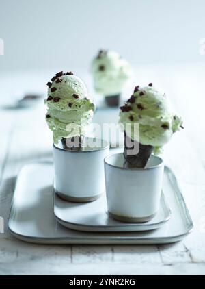 Gelato fatto in casa alla menta piperita ripieno in tre coni di cioccolato su sfondo bianco in legno Foto Stock