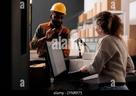 Dipendenti diversi del magazzino che discutono del controllo di qualità delle merci lavorando al rapporto di inventario, stando al banco di vendita nel magazzino. Colleghi che controllano l'ordine del cliente preparano i dettagli di spedizione Foto Stock