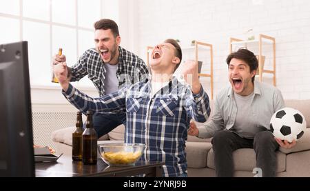 I vincitori. Amici eccitato guardando la partita di calcio a casa Foto Stock