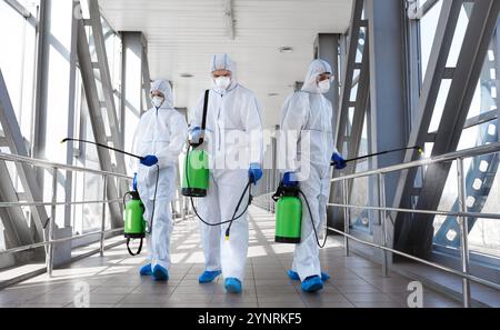 Team di virologi professionisti in tute protettive pronte per la disinfezione Foto Stock