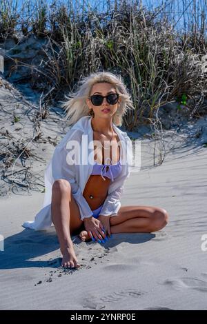 Una donna stupenda si rilassa sulla spiaggia in un bikini che mette in risalto le sue curve. Le piace l'acqua fresca e si crogiola sotto il sole caldo, immergendosi nella sua Foto Stock