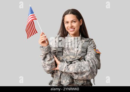 Soldato femminile con bandiera USA su sfondo grigio Foto Stock