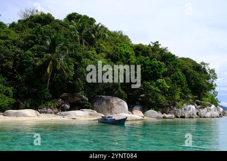 Isole Indonesia Anambas - Dinkor Island con barca da pesca e grandi rocce Foto Stock