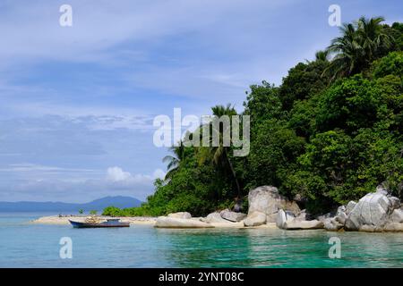 Isole Indonesia Anambas - Dinkor Island con spiaggia di barche da pesca e grandi rocce Foto Stock