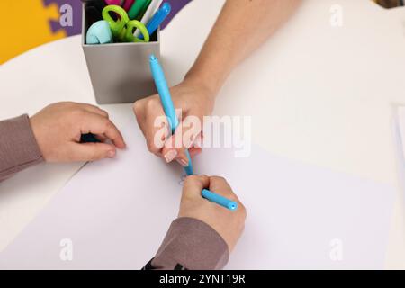 Terapia autistica. Psicologo e bambino che disegna un quadro a tavola, primo piano Foto Stock