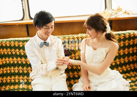 Sposo che posiziona l'anello sul dito della sposa Foto Stock