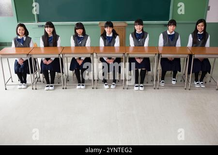 Ragazze sedute in fila di scrivanie Foto Stock