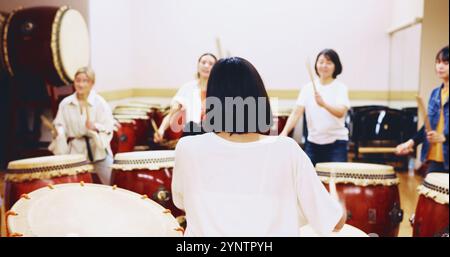 Giapponese, batteria e persone in pratica per la musica su strumenti per prestazioni, creatività o classe. Taiko, donne o batteriste che imparano in band Foto Stock