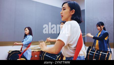 Tradizione giapponese, batteria e persone con musica o strumento per prestazioni, creatività o classe. Taiko, donne o batteriste che imparano in band Foto Stock