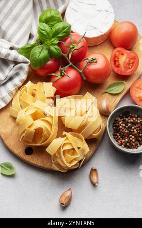 Ingredienti freschi disposti su un tagliere di legno, pronti per preparare un piatto di pasta Foto Stock
