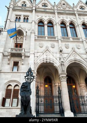 Uno stupefacente edificio storico con intricati dettagli architettonici, caratterizzato da una prominente statua del leone e finestre ad arco. Parlamento ungherese Buildi Foto Stock