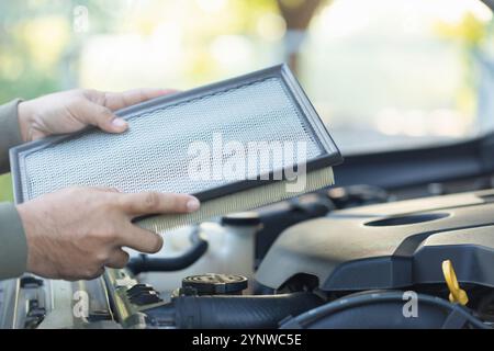 Il proprietario di un'auto è in possesso di un filtro dell'aria per l'esame. L'importanza dell'ispezione, della pulizia e della sostituzione regolari dei filtri dell'aria dell'auto sottolinea la manutenzione Foto Stock