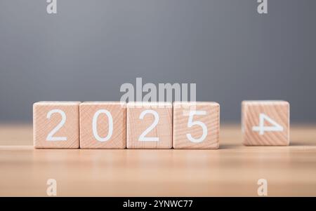 Hand sostituisce "2024" con "2025" utilizzando blocchi numerici, simboleggiando la transizione verso il nuovo anno, rappresentando il cambiamento, il progresso e i PA in corso Foto Stock