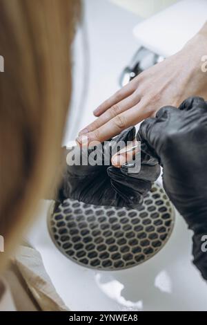 Maestro di manicure, che lavora nel salone di bellezza modellando le unghie di una giovane cliente femminile. Foto di alta qualità Foto Stock