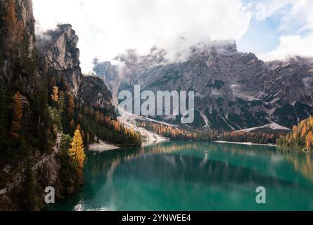 La luce del sole illumina un larice sulle rive del lago di braies in un paesaggio autunnale Foto Stock