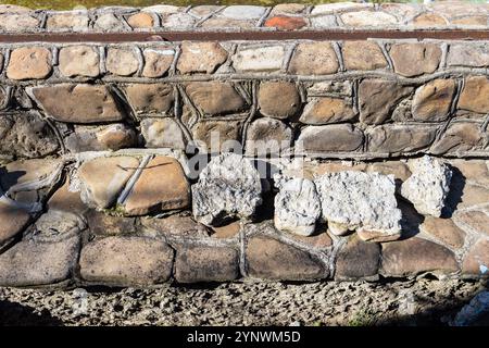 rivestimento di rocce selvagge del fiume che cadono dal muro durante il giorno di sole Foto Stock