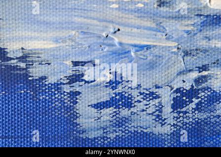 Un sorprendente dipinto astratto con tratti audaci di vernice acrilica blu, oro e bianca su una tela testurizzata. Foto Stock