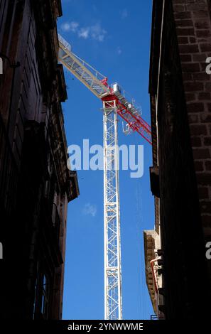 gru da costruzione tra due edifici bui, taranto, italia Foto Stock