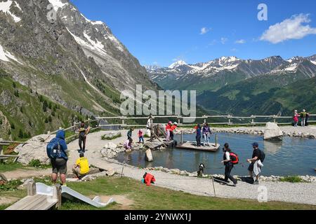 Gente che si diverte ad attraversare uno stagno su una zattera alla stazione della funivia Pavillon (2173 m) della Skyway Monte bianco in estate, Courmayeur, Aosta, Italia Foto Stock