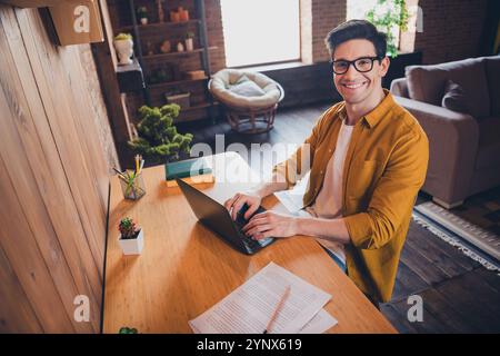 Giovane uomo con una camicia elegante che si gode una giornata di lavoro produttiva a casa in un ambiente confortevole e accogliente Foto Stock