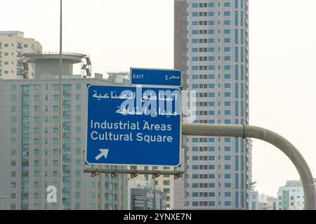 Indicazioni stradali direzionali in arabo e inglese sul ponte di Sharjah City, Emirati Arabi Uniti. Foto Stock