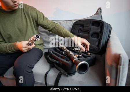 Man Hands mette il clarinetto nero smontato in un caso speciale, ispeziona parti del flauto dopo averlo suonato Foto Stock