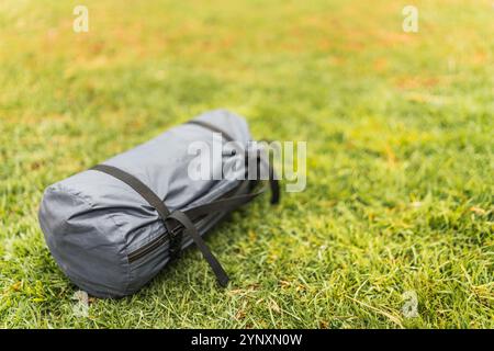 Borsa per tenda grigia su erba verde illuminata con luce naturale nella catena montuosa delle Ande Foto Stock