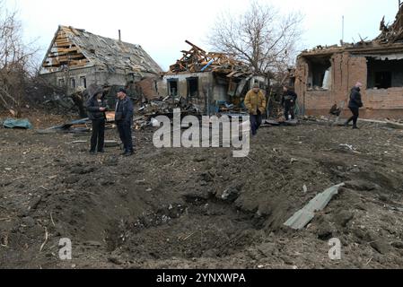 REGIONE DI DONETSK, UCRAINA - 26 NOVEMBRE 2024 - i residenti locali stanno accanto al cratere di conchiglia causato da un attacco missilistico guidato russo nel villaggio di Yasnohirka vicino a Kramatorsk, regione di Donetsk, Ucraina orientale Foto Stock