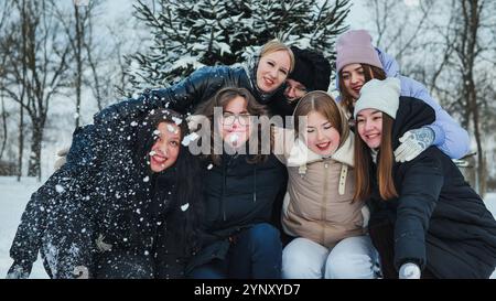 Le studentesse e uno scolaro si divertono sulla neve durante un servizio fotografico invernale nel parco Foto Stock