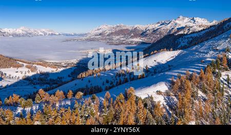 Vista aerea della valle del Champsaur in autunno con pendii innevati, larici dorati e villaggio di Ancelle. Hautes-Alpes, Alpi francesi, Francia Foto Stock