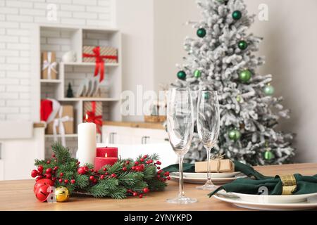 Impostazione della tavola di Natale con candele brucianti e corona in cucina Foto Stock