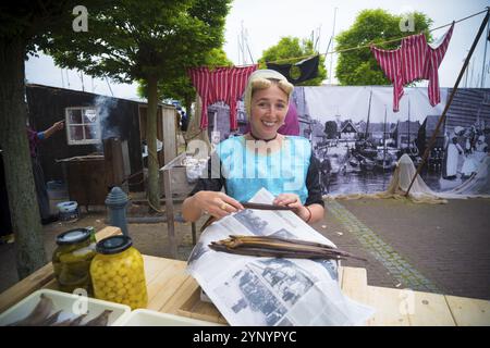 URK, PAESI BASSI, 19 MAGGIO 2018: Donna sconosciuta in abiti tradizionali che vende anguille affumicate nei giorni Urker annuali. Urk è una delle zone di pesca più famose Foto Stock