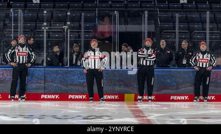 Linesperson Tobias Schwenk, Hauptschiedsrichter Christopher Schadewaldt, Hauptschiedsrichter Roman Gofman und Linesperson Lukas Pfriem sehen sich das Video AN, welches zur Ehrung von Maximilian Kastner (EHC Red Bull Muenchen, #93), nicht im Bild, auf dem Wuerfel eingespielt wird. GER, EHC Red Bull Muenchen vs. Schwenninger Wild Wings, Eishockey, DEL, 20. Spieltag, Saison 2024/2025, 26.11.2024. Foto: Eibner-Pressefoto/Heike Feiner Foto Stock