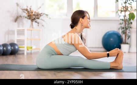 L'esperta insegnante di fitness club esegue paschimottanasana Foto Stock