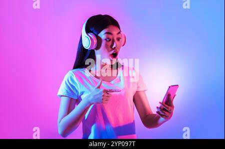 Lady in Headsets punta il dito verso lo smartphone Foto Stock