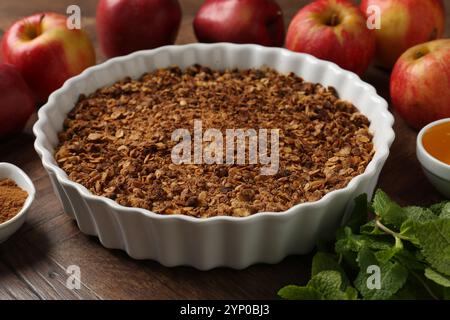 Gustosa croccante di mele in teglia da forno e ingredienti su tavola di legno, primo piano Foto Stock