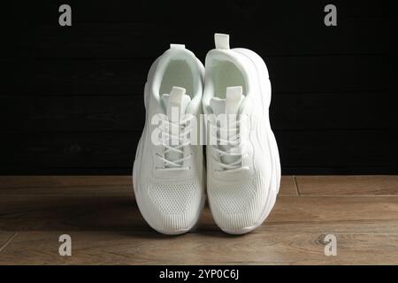 Un paio di eleganti sneaker bianche in aria sul pavimento su sfondo scuro Foto Stock