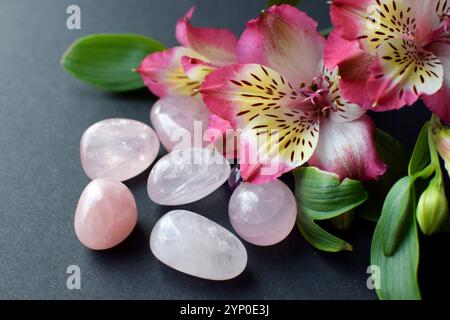 Cristalli di quarzo rosa e fiori di alstroemeria su sfondo grigio. Foto Stock