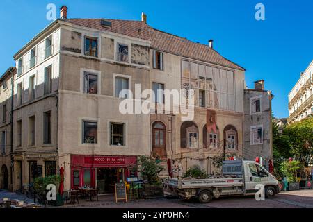 Piccoli caffè ed edifici di fronte alla chiesa Eglise Saint-Roch de Montpellier a Montpellier, Francia Foto Stock