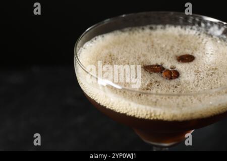 Deliziosi martini espresso con chicchi di caffè in vetro su sfondo nero, primo piano Foto Stock