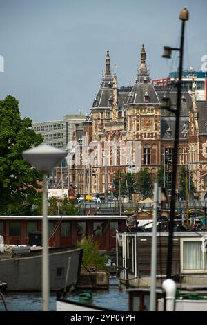 09.08.2024, Paesi Bassi, Olanda settentrionale, Amsterdam - Vista dall'ex estuario dell'IJ alla stazione Centraal, con case galleggianti davanti. 00A230619D791CARO Foto Stock