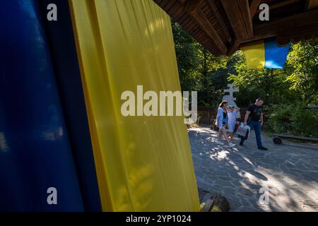 25.08.2024, Ucraina, Lviv Oblast, Leopoli - bandiere ucraine sulla chiesa di legno Shevchenkivskyi Hay museo all'aperto con architettura storica Ucraina Foto Stock