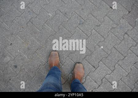 Scarpe casual indossate con stile sul pavement City, abbinate a jeans alla moda per un look chic Foto Stock