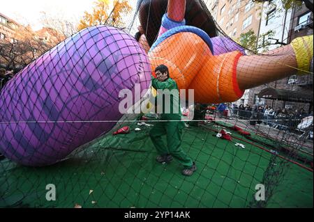 New York, Stati Uniti. 27 novembre 2024. Un membro dell'equipaggio dell'inflazione di Macy spinge il piede di Dora il pallone Explorer tenuto sotto una rete durante l'inflazione annuale del pallone alla vigilia della Macy's Thanksgiving Day Parade del 2024, New York, NY, 27 novembre 2024. Migliaia di newyorkesi e turisti hanno la possibilità di guardare più di 30 palloncini mentre si gonfiavano e si preparavano per la 98a edizione della Parata il 28 novembre. (Foto di Anthony Behar/Sipa USA) credito: SIPA USA/Alamy Live News Foto Stock