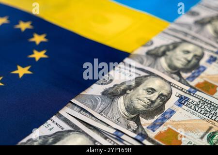 Aiuto finanziario all'Ucraina. Assistenza finanziaria, donazione, investimenti denaro su sfondo bandiera Ucraina. Dollari sulle bandiere ucraine ed europee. Foto Stock