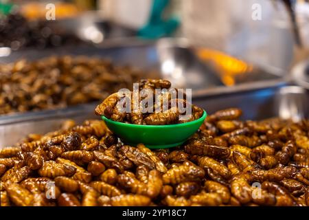 Larve di insetti fritti in vendita sul mercato in Cambogia. Esotico snack thailandese di strada. Foto Stock