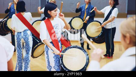 Giapponese, di apprendimento o persone con batteria per musica su strumento per prestazioni, creatività o classe. Taiko, donna o batterista femminile in band per suonare Foto Stock