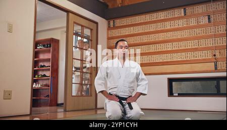 Arti marziali, inginocchiarsi e uomo giapponese con rispetto, onore e galateo di karate nel dojo. Giappone, addestramento al combattimento e studio di combattimento con lo sport Foto Stock