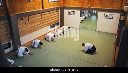 Inchino, saluto e persone in studio di arti marziali per lezioni di pratica, allenamento o autodifesa. Cultura, karate e gruppo di studenti con rispetto o. Foto Stock