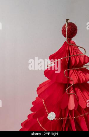 Collana di canapa dorata su un albero a nido d'ape di Natale di carta rossa. Foto Stock